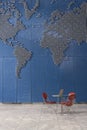 Laptop on table in empty office with world map on wall Royalty Free Stock Photo