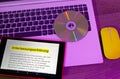 Laptop and tablet on which a text with a declaration of omission is displayed with yellow mouse in violet optics