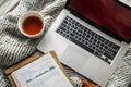 Laptop and tea with analytics notes on cozy knitted blanket, relaxed work from home scene Royalty Free Stock Photo