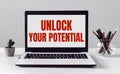 Laptop with UNLOCK YOUR POTENTIAL text on modern office background Royalty Free Stock Photo