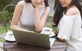 Laptop used by two beautiful young women, two coworkers meet in