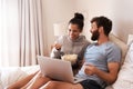 Laptop, watching movie and popcorn with laughing couple in bed for streaming, relax or internet. Subscription, happy or Royalty Free Stock Photo