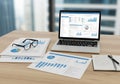 Laptop on a wooden desk displaying various charts and graphs in a Royalty Free Stock Photo