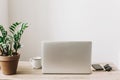 Laptop on wooden desktop with phone, notebook, coffee cup and pl Royalty Free Stock Photo