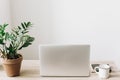 Laptop on wooden desktop with phone, notebook, coffee cup and pl Royalty Free Stock Photo