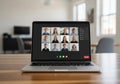 A laptop on a wooden table displays a video conference call with Royalty Free Stock Photo