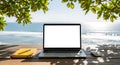 Laptop on a wooden table by the sea with a notebook and mouse, perfect for remote work background Royalty Free Stock Photo