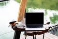 Laptop on wooden table on terrace by lake