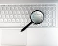 Laptops keyboard through magnifying glass. Internet search and keywording concept