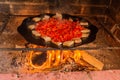 Lard and tomatoes on the fire. Bacon and tomato slices are fried in a skillet over a fire