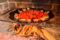 Lard and tomatoes on the fire. Bacon and tomato slices are fried in a skillet over a fire