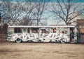 Large abandoned bus with painted street art and graffiti