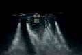 Large agricultural drone sprays on a black background, streams of drops