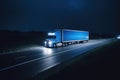 A large american semi-trailer moves along the highway at night with its headlights on.