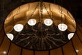 A large antique vintage round metal chandelier of bronze color with decorative elements hangs on the ceiling of a golden Royalty Free Stock Photo