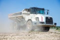 Large articulated dump truck with a white cab at a construction site during excavation work against blue sky