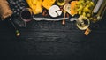 A large assortment of cheeses, brie cheese, gorgonzola, blue cheese, grapes, honey, nuts, red and white wine, on a wooden table. Royalty Free Stock Photo