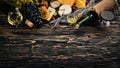 A large assortment of cheeses, brie cheese, gorgonzola, blue cheese, grapes, honey, nuts, red and white wine, on a wooden table. Royalty Free Stock Photo