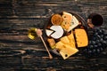 A large assortment of cheeses, brie cheese, gorgonzola, blue cheese, grapes, honey, nuts, red and white wine, on a wooden table. Royalty Free Stock Photo