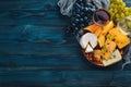 A large assortment of cheeses, wine, honey, nuts and spices, on a blue wooden table. Top view.