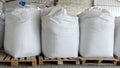 Large bags of grain and flour are stored in an industrial warehouse.