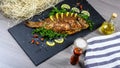 Large baked carp with herbs, lemon and spices. flat top view, copy text menu