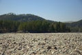 The large bank of the Katun River is covered with round stones with high mountains in the background. Gorny Altai, Siberia, Russia Royalty Free Stock Photo