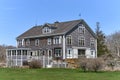 A large barn converted to a summer house with weathered wood shingles and white trim