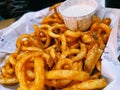 A large basket of curly fries and ranch dressing