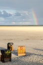 Large beach with beach chairs an rainbow