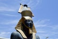 Large beautiful stone statue of a black proud majestic pharaoh in a golden cap, a crown in the shape of a jug against a blue sky