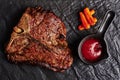 Large beef t bone steak with sauce at black stone background