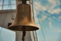 A large bell made of bronze on the ship`s deck with sky and clouds Royalty Free Stock Photo