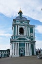 A large bell tower with a belfry and a clock. The woman is wearing a gauze mask.