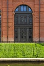 Large black door in red brick building against green grass background Royalty Free Stock Photo