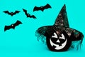 Large Black Halloween Pumpkin with cute smiling face wearing witch hat looking at flying paper bats over blue background. Royalty Free Stock Photo