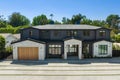 a large black house with white and brown accents and brown garage doors Royalty Free Stock Photo