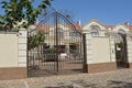 A large black iron gate with a forged pattern of metal rods and a gray concrete fence wall Royalty Free Stock Photo