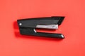 Large black office stapler on a red background. Stationery for stapling paper. Accessories for work Royalty Free Stock Photo