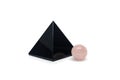 Large black pyramid of obsidian stone and small ball of rose quartz. Reiki concept. Isolated on white background Royalty Free Stock Photo