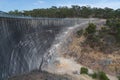 A large black reservoir concrete wall with handrails and a small building at the bottom Royalty Free Stock Photo