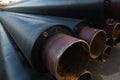 Large black steel pipe with heat insulation on the construction site close up in a plastic tube wrapper Royalty Free Stock Photo