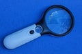 Large black white plastic magnifier on a blue table Royalty Free Stock Photo