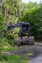 A large black and yellow machine is driving through a forest Royalty Free Stock Photo