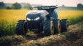 Large, black and yellow tire-like vehicle is driving through field of tall grass. The vehicle has two sets of wheels on front and