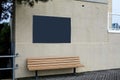Large blank black sign on a white brick wall over a bench on a boardwalk Royalty Free Stock Photo