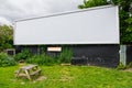 A large blank empty billboard on side of the road with bench in