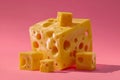 Large block of yellow cheese with multiple holes and several small cheese cubes arranged on a pink background creating a vibrant Royalty Free Stock Photo
