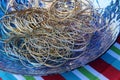 Large blue glass bowl filled with simple gold and silver bangle bracelets Royalty Free Stock Photo