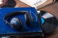 Large blue headphones on a stack of vintage vinyl records, next to a book titled Jazz.